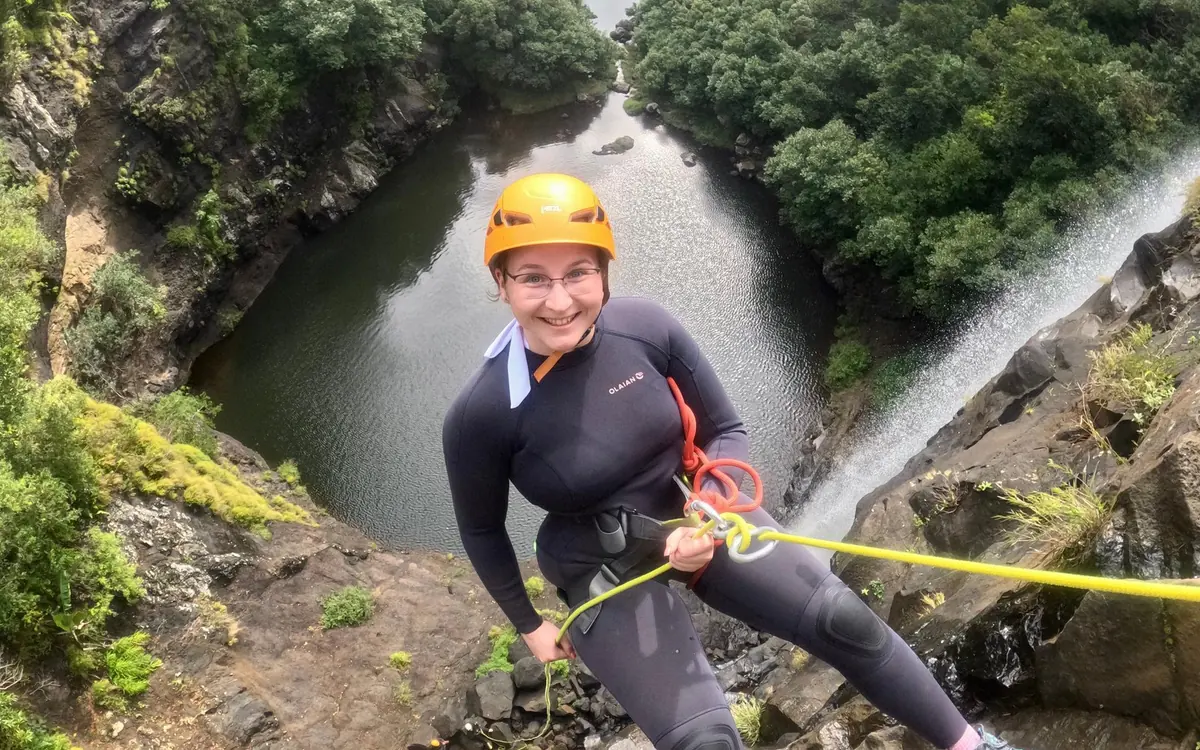 Une femme en combinaison et casque orange sur une corde au-dessus d'un bassin